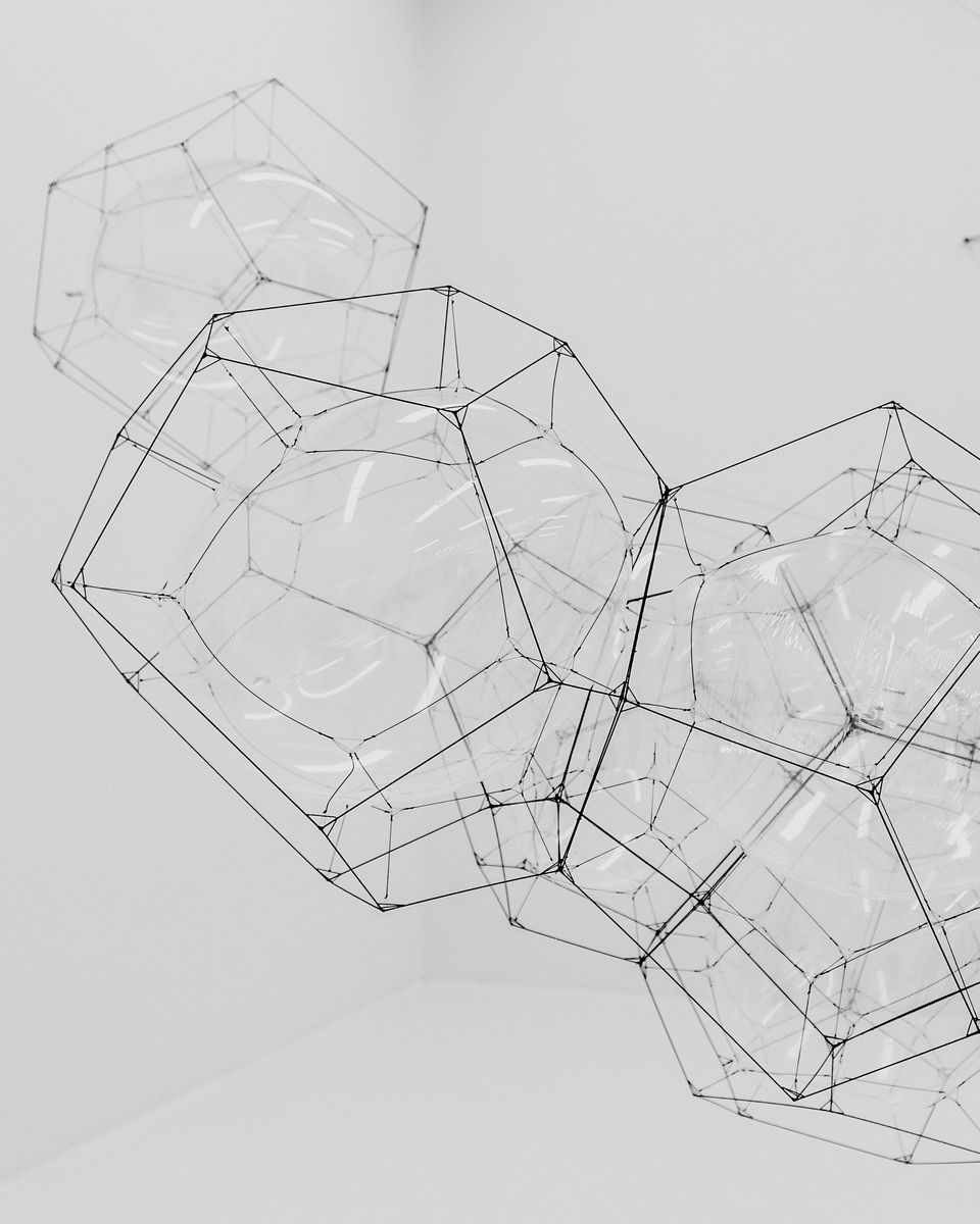 Wireframe polyhedra suspended in a white room